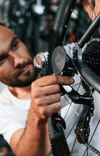 Checking the wheel and brake system. Repair man in bicycle shop, working in store Checking the wheel and brake system. Repair man in bicycle shop, working in store.